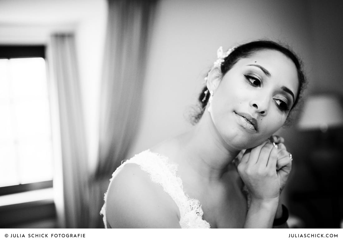 Braut legt Ohrringe an vor standesamtlicher Trauung auf Sportschloss Velen im weißen Saal der Orangerie