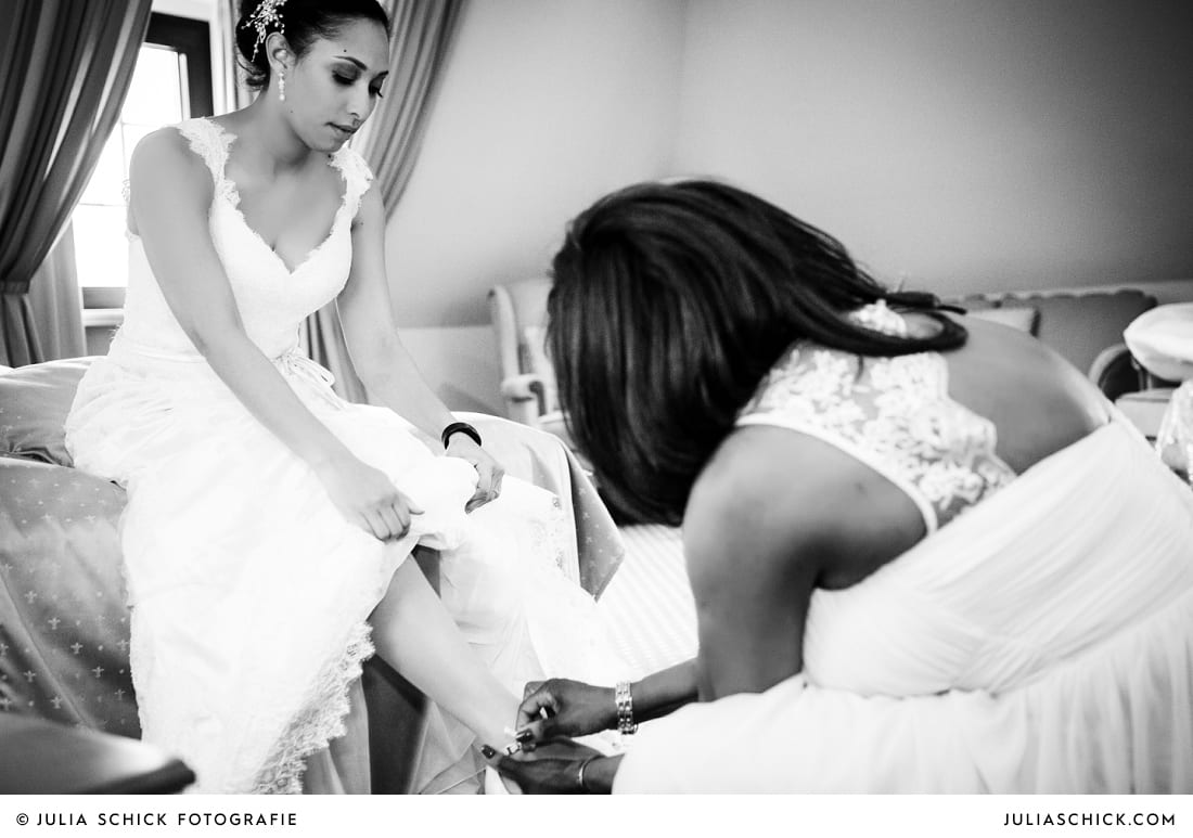 Brautmutter zieht Braut die Schuhe an auf Hotelzimmer standesamtlicher Trauung auf Sportschloss Velen im weißen Saal der Orangerie