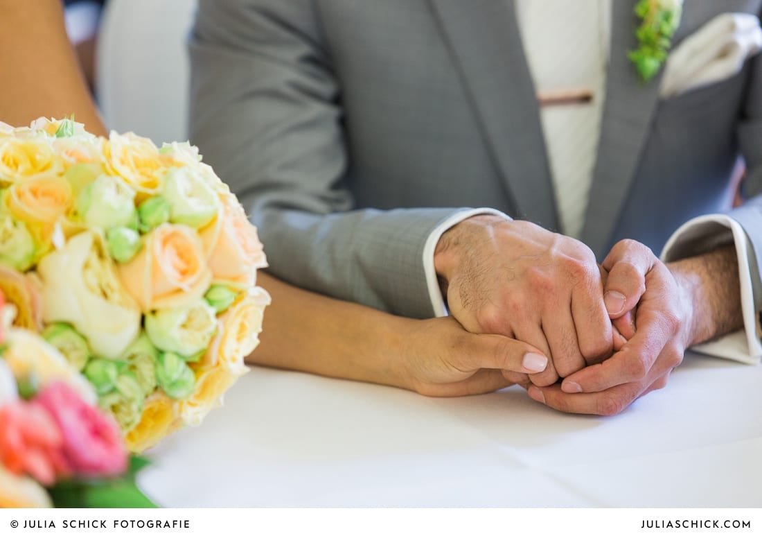 Hände des Brautpaares bei standesamtlicher Trauung auf Sportschloss Velen im weißen Saal der Orangerie