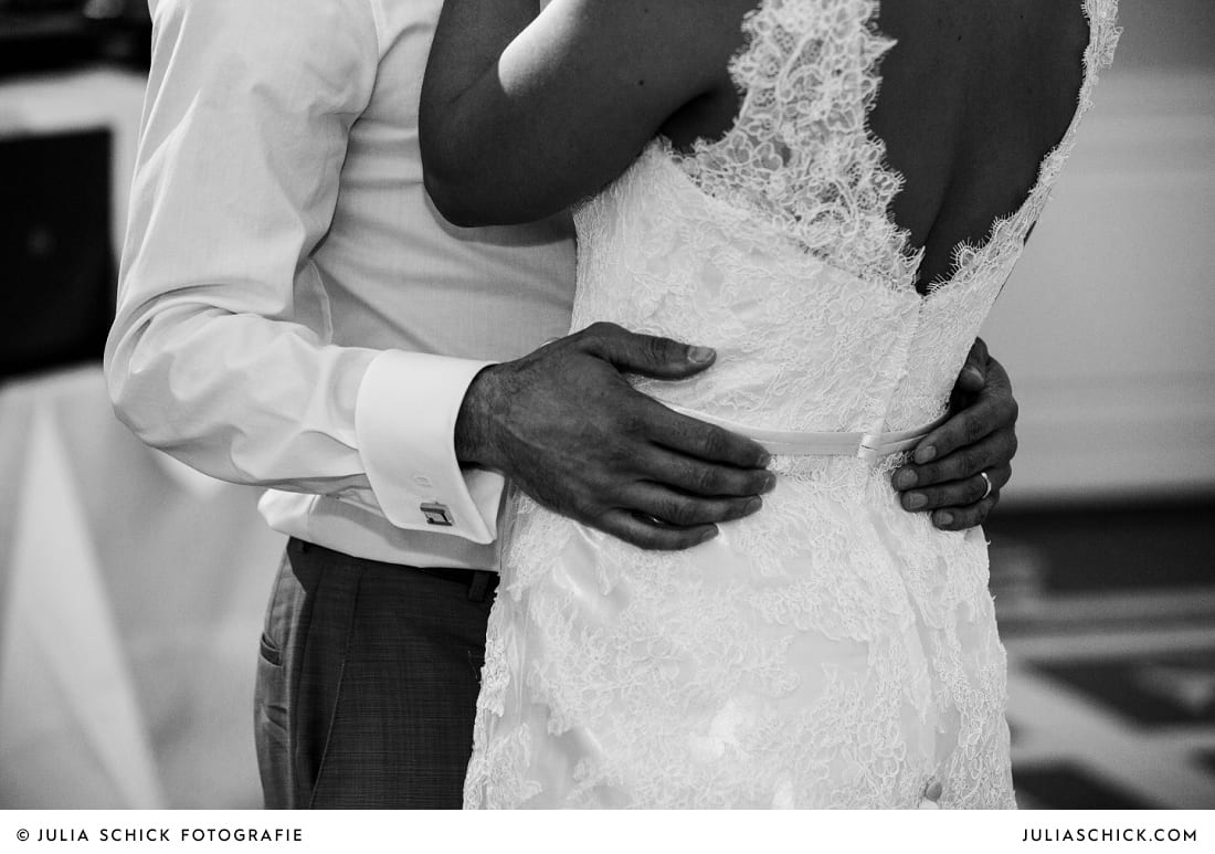 Hände des Bräutigams auf Kleid der Braut bei Hochzeitsfeier in der Remise des SportSchloss Velen