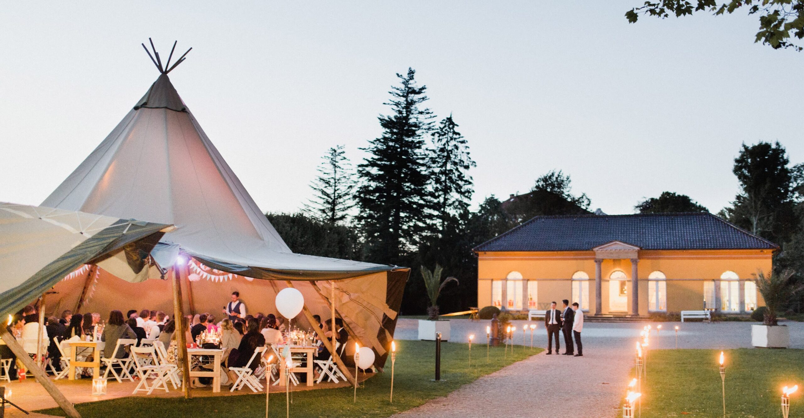 Tipi Zelt mit Hochzeitsgästen bei Hochzeitsfeier an der Orangerie von Schloss Glücksburg bei Flensburg
