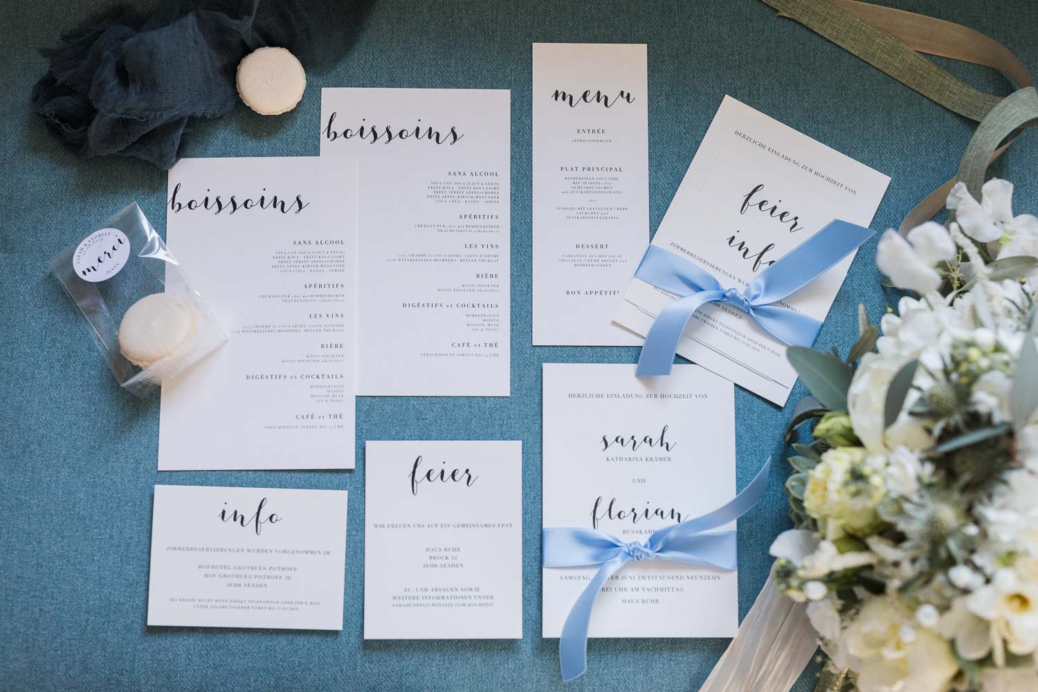Hochzeitspapaterie auf blauem Hintergrund bestehend aus Einladungskarten, Menükarten und Getränkekarten für eine Hochzeitsfeier auf Haus Ruhr in Senden