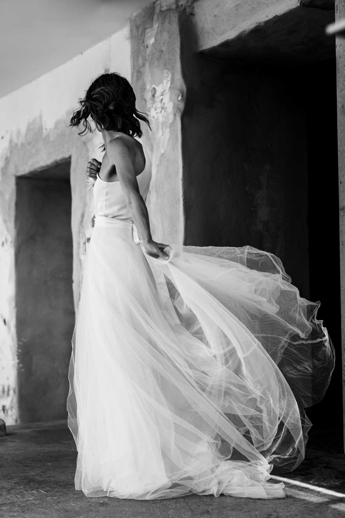 Braut dreht sich im Kreis bei Hochzeitsfotoshooting im Flur des Factory Hotels in Münster. Das Foto ist in schwarz weiß. Der Rock des Brautkleids dreht sich im Wind. Das Hochzeitsfoto ist in schwarz-weiß.