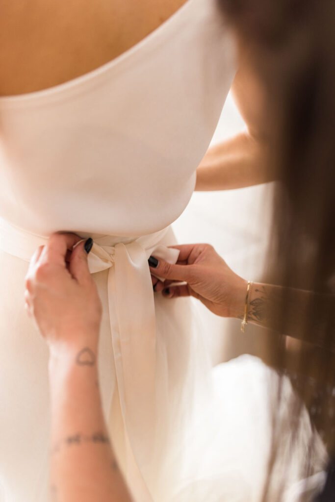 Braut beim Anziehen des Brautkleids beim Getting Ready in einer Suite des Factory Hotels Münster