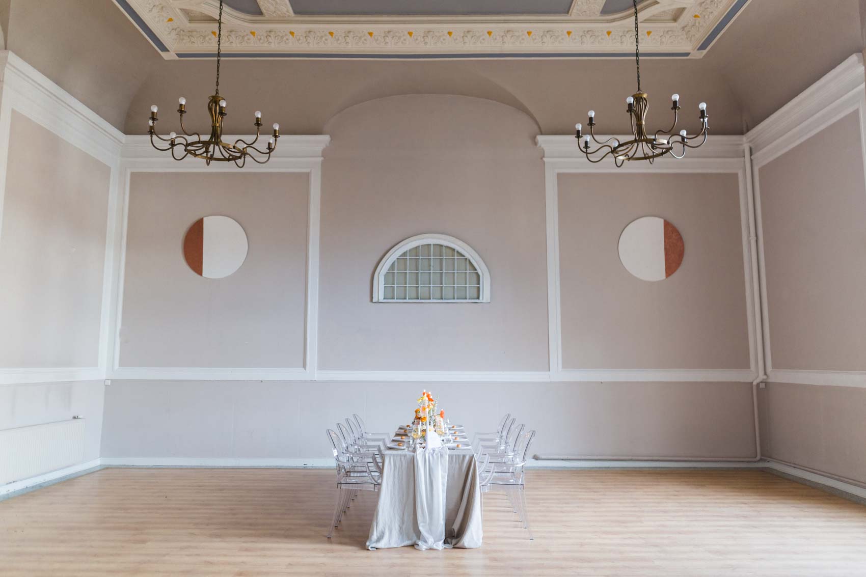 Gedeckter Hochzeitstisch mit Leinentischdecke und Ghostchairs im großen Saal der Kneisterei Münster. Blumendekoration in lila, orange und gelb