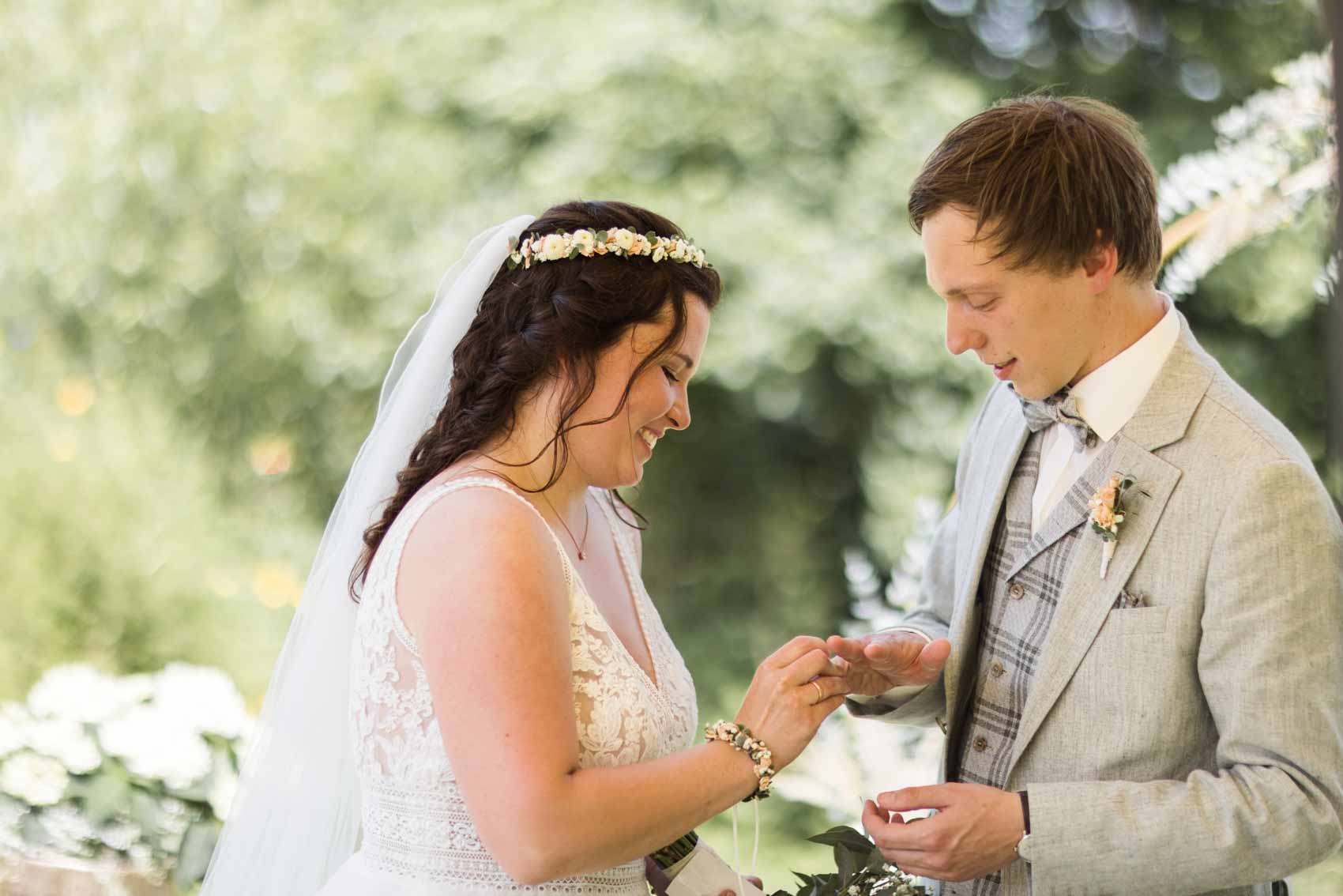 Hochzeitspaar tauscht Ringe bei einer freien Trauung im Garten der Hochzeitslocation Seescheune am Bulderner See in Dülmen