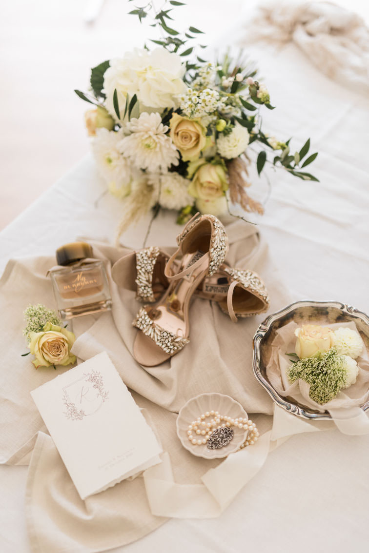 Brautschuhe mit glitzernden Steinen arrangiert zusammen mit Brautstrauß und Brautschmuck mit Perlenkette