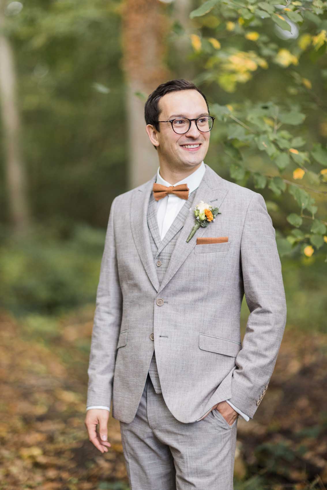 Bräutigam mit grauem Anzug und orangener Fliege und orangenem Einstecktuh