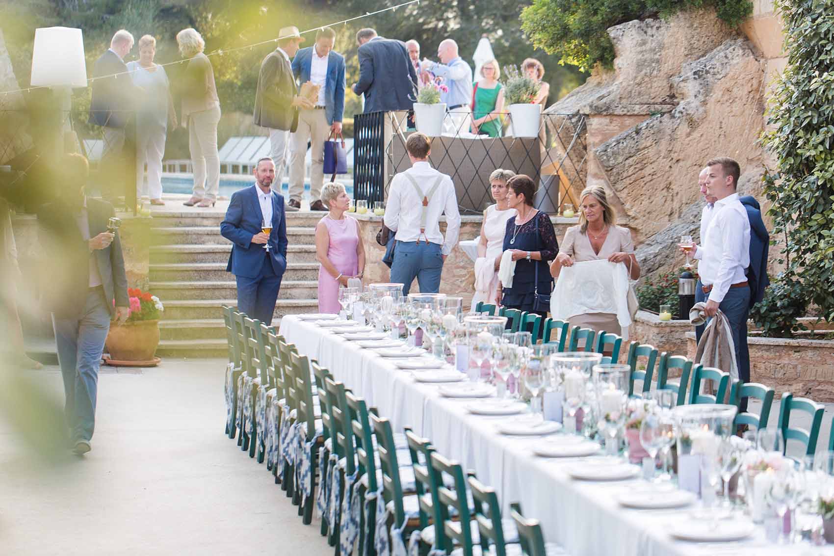 Gäste suchen an einem langen, dekorierten Tisch bei einer Hochzeit auf Mallorca ihren Platz. 